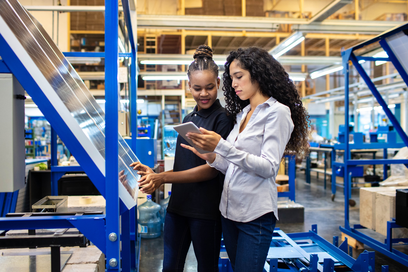 Two women looking at a tablet in a manufacturing setting