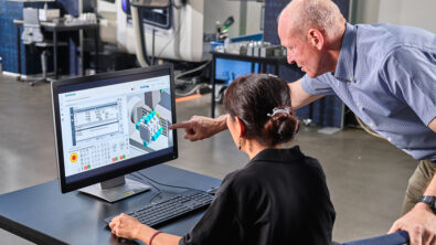 Women sitting at computer with man looking over her shoulder and pointing.