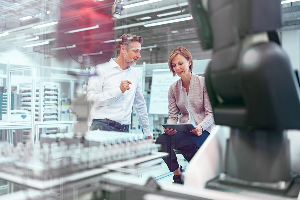 Businessman and businesswoman talking in a modern factory hall