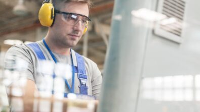 focused worker in protective workwear at computer in factory