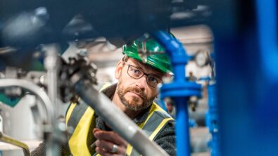 Man wearing green helmet examining a piece of machinery