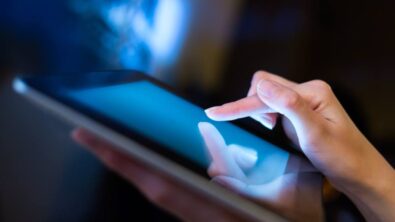 Closeup of a finger touching a tablet with a dark background