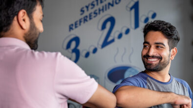 Indian man bumping elbows with his colleague in the office