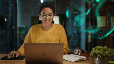 Woman working on a laptop using cloud solutions, overlayed with digital superimposition particle effect